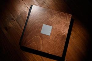 Photo book in a wooden cover on a wooden table. Hard light