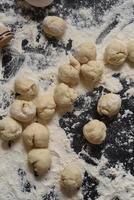 Pieces of dough in the form of a circle on a black background. Modeling of dumplings. Traditional Ukrainian cuisine. photo