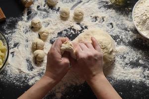 Pizza dough or baking on a dark black background of wood. Baking bread, pizza, pasta. Top view, horizontal photo