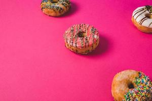close up of a pink donut on a pink background