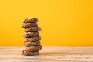 a tower of  chocolate chip cookies on a yellow background