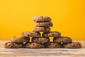 pirámide hecha de galletas con trocitos de chocolate sobre un fondo amarillo foto