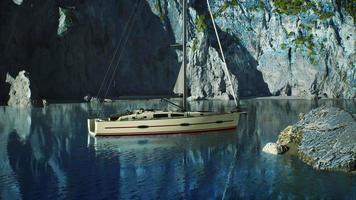 White yacht anchored in a bay with rocky cliffs video