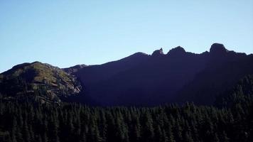 panoramic aerial view of rocky ridge among green forest at sunset video