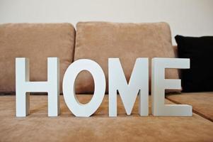 Letras blancas de madera en casa en el sofá cama de la esquina del café en la sala de luz foto
