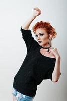 Studio portrait of red haired girl on black blouse and jeans shorts with bright dark make up photo