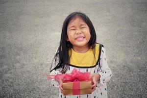 Cute asian girl holding gift box for giving in holidays. Holidays, giving, present concept. photo