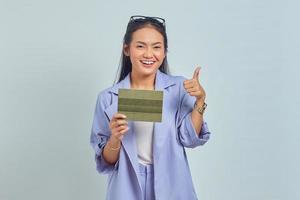 Portrait of cheerful young Asian woman holding vehicle book and showing thumbs up gesture isolated on white background photo