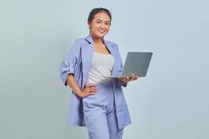 Portrait of cheerful young Asian woman using laptop and looking at camera isolated on white background photo