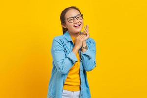 el retrato de una joven estudiante asiática sonriente vestida de denim se siente alegre, tiene dientes blancos, mirando la cámara con confianza aislada en un fondo amarillo. concepto de estilo de vida de emociones sinceras de personas