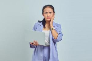 Portrait of pensive young Asian woman holding laptop and holding chin with palms isolated on white background photo