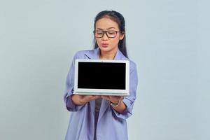 Portrait of cheerful young Asian business woman showing blank laptop screen to present products isolated on white background photo