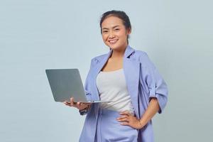 Portrait of cheerful young Asian woman using laptop and looking at camera isolated on white background photo