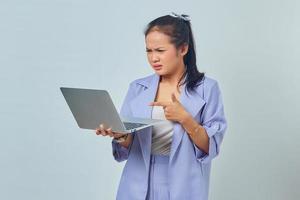 Portrait of confused young Asian woman pointing fingers at a laptop isolated on white background photo