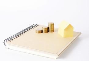 pila de monedas y modelo de casa amarilla en el libro para el concepto de negocio de préstamos hipotecarios