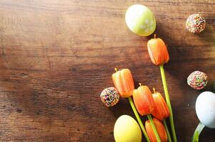 Easter festival concept with fancy eggs and tulips flower on wooden table backgrounds above photo