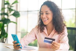 Hermosa mujer latina con smartphone con tarjeta de crédito foto