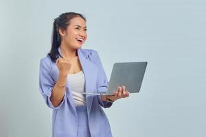 Portrait of smiling young Asian woman holding a laptop and celebrating success isolated on white background photo