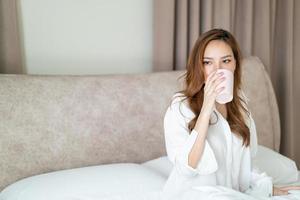 portrait beautiful woman wake up and holding coffee cup or mug on bed photo