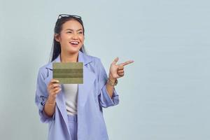 Portrait of cheerful young Asian woman pointing finger at empty space and holding vehicle book isolated on white background photo