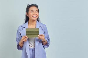 Portrait of smiling young Asian woman holding vehicle book in good mood and looking at empty space isolated on white background photo