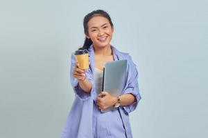 Portrait of smiling young Asian woman holding laptop and coffee isolated on white background photo