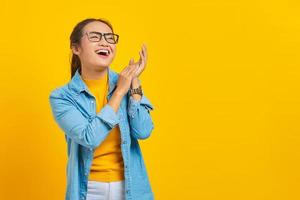 Portrait of smiling young Asian woman student in denim clothes feels joyful has white teeth, looking at camera with confident isolated on yellow background. People sincere emotions lifestyle concept photo