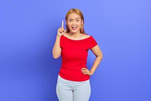 Portrait of excited beautiful young Asian woman pointing to the copy room isolated on purple background photo