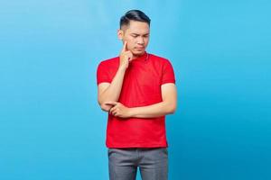 Portrait of pensive young Asian man looking seriously thinking about a question isolated on blue background photo