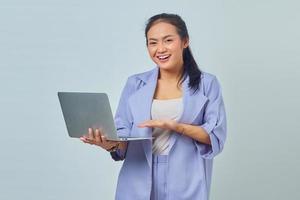 Portrait of smiling Asian woman pointing at laptop with palms on white background photo