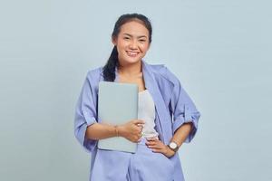 Portrait of smiling young Asian woman holding a laptop and looking at camera isolated on white background photo