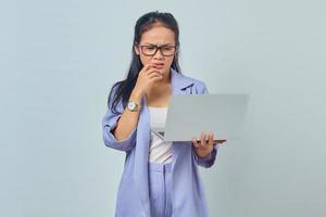 Portrait of scared young Asian woman standing using laptop and biting nails isolated on white background photo