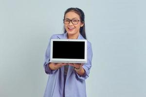 Portrait of cheerful young Asian business woman showing blank laptop screen to present products isolated on white background photo