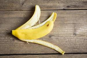 cáscara de plátano sobre fondo de madera, cáscara de plátano madura en el suelo - vista superior foto