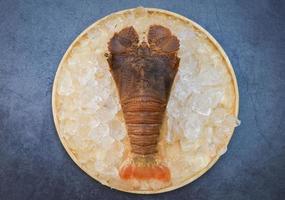 Raw flathead lobster shrimps on ice, fresh slipper lobster flathead for cooking on dark background in the seafood restaurant or seafood market, Rock Lobster Moreton Bay Bug photo