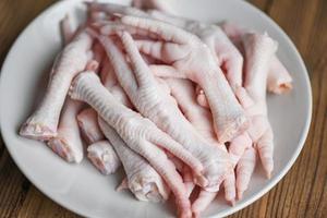 Chicken feet on white plate, Fresh raw chicken feet for cooked food on the wooden table kitchen background photo