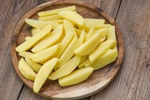 fresh raw potato wedges, chopped potatoes for cooked food on wooden bcakground photo