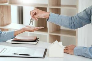 agente que entrega las llaves de la casa al cliente después de firmar el acuerdo de propiedad, en relación con la oferta de préstamo hipotecario y el seguro de la casa.