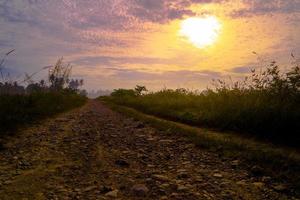 Rural landscape with dirt road at sunrise photo