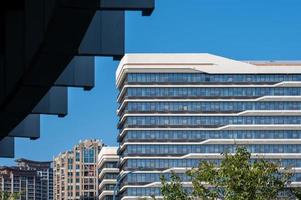 parte de los modernos edificios mixtos de vidrio urbano está en el cielo azul y hace buen tiempo foto