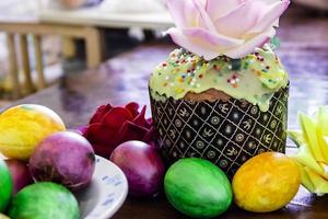 Sweet Easter cakes with colorful eggs on table in room photo