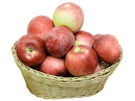 Ripe red apple in wicker basket isolated on white photo