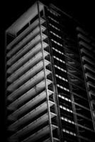 Black and white image of an unfinished multistory building in a low key. Unfinished building view at night. photo