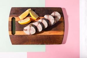 la caballa fresca cortada en trozos se encuentra en una tabla de cocina sobre un fondo de color brillante foto