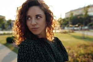 Portraits of a charming red-haired girl with freckles and a pretty face. The girl poses for the camera in the city center. She has a great mood and a sweet smile photo