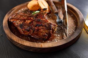 medium rare Steak on bone Veal rib with potato on a wooden plate photo