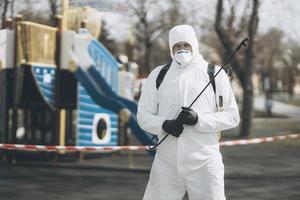 Cleaning and Disinfection on the playground in the sity complex amid the coronavirus epidemic Teams for disinfection efforts Infection prevention and control of epidemic Protective suit and mask photo