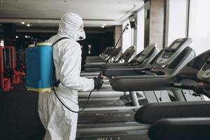 Cleaning and Disinfection in crowded places amid the coronavirus epidemic Gym cleaning and disinfection Infection prevention and control of epidemic. Protective suit and mask and spray bag photo