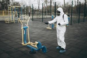 Cleaning and Disinfection on the playground in the sity complex amid the coronavirus epidemic Teams for disinfection efforts Infection prevention and control of epidemic Protective suit and mask photo