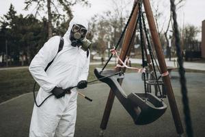 Cleaning and Disinfection on the playground in the sity complex amid the coronavirus epidemic Teams for disinfection efforts Infection prevention and control of epidemic Protective suit and mask photo